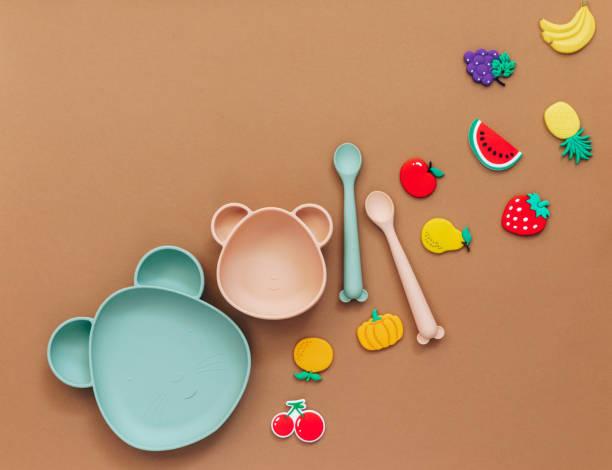 istock Cute Flat lay composition with baby accessories and tableware for food on light background. First food for kids concept 1304605167