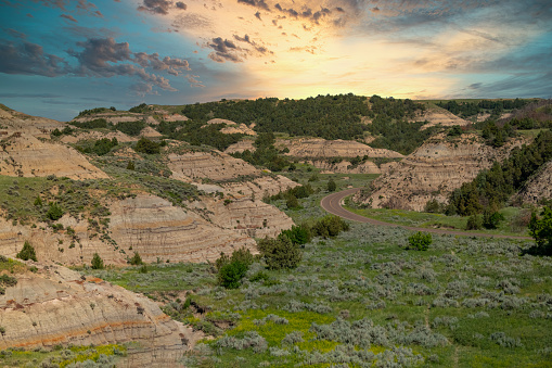 Theodore Roosevelt National Park lies where the Great Plains meet the rugged Badlands near Medora, North Dakota, USA.  The park's 3 units, linked by the Little Missouri River is a habitat for bison, elk and prairie dogs.  The park's namesake, President Teddy Roosevelt once lived in the Maltese Cross Cabin which is now part of the park.  This picture of the badlands at sunset was taken from the Painted Canyon Overlook.