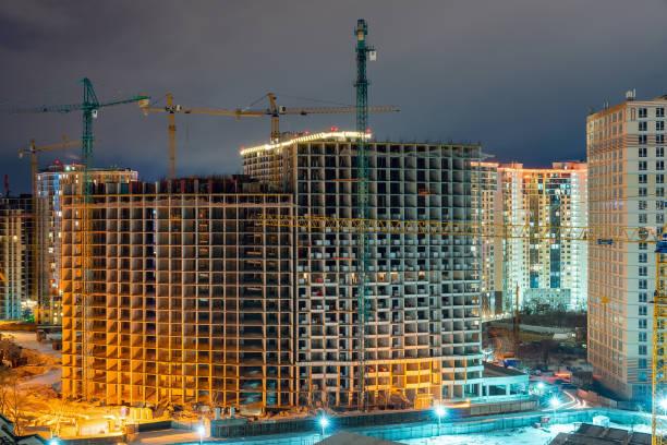 istock Construction site, cranes and multi-storey unfinished houses at night in winter 1304606000