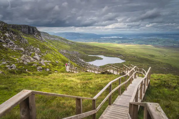Photo of People enjoying a walk on steep stairs of wooden boardwalk in Cuilcagh Mountain Park