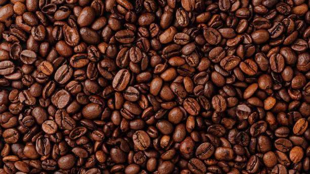 Roasted coffee beans background texture. Overhead view Coffee beans texture. Standing out from the crowd concept. coffee stock pictures, royalty-free photos & images