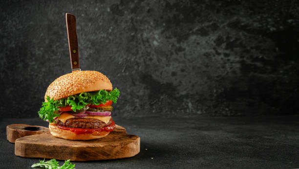 istock Beef burger with knife on wooden board. 1304608094