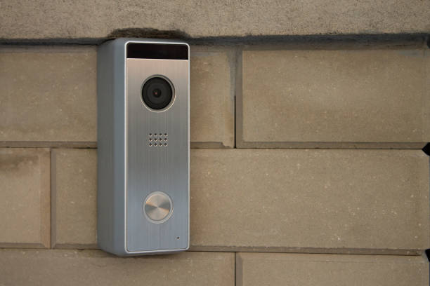 Silver intercom panel with video camera on a brick beige fence pillar of a private house Silver intercom panel with video camera, on a brick beige fence pillar of a private house doorbell photos stock pictures, royalty-free photos & images