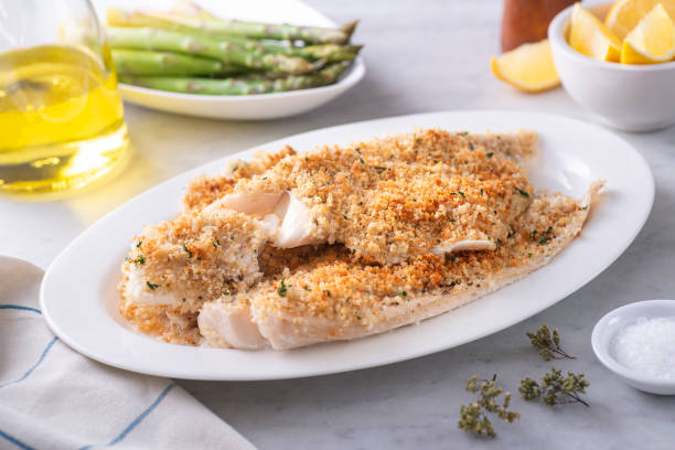 Panko Crusted Baked Haddock A plate of delicious panko breadcrumb crusted baked haddock with asparagus and lemon. hake stock pictures, royalty-free photos & images