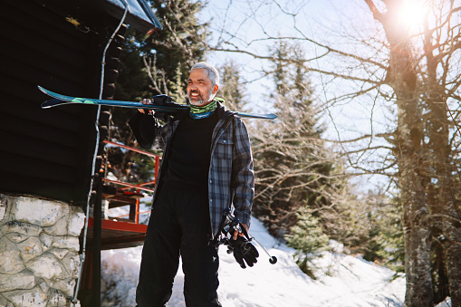 Active older man skiing on the mountain top. He is on the remote place, away from the crowds, enjoying his day on the mountain during the covid-19 pandemic.