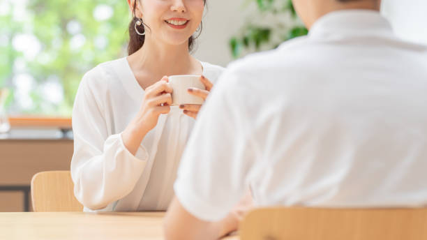 young japanese couple drinking tea in kitchen young japanese couple drinking tea in kitchen japanese girlfriends stock pictures, royalty-free photos & images