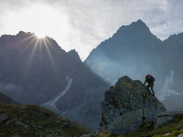 istock Mountaineer scrambles up mountain slope 1304611971