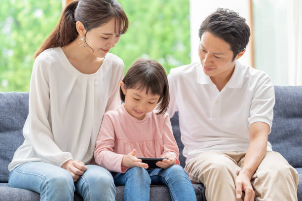 居間でスマートフォンを使う若い日本人家族 - two generation family 写真 ストックフォトと画像