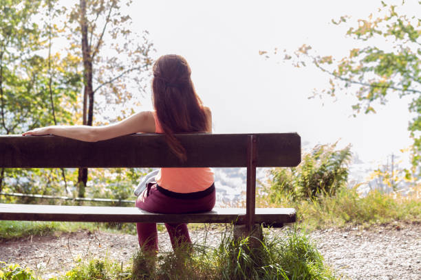 istock a girl sits on a bench in the forest, her back to the camera 1304614763