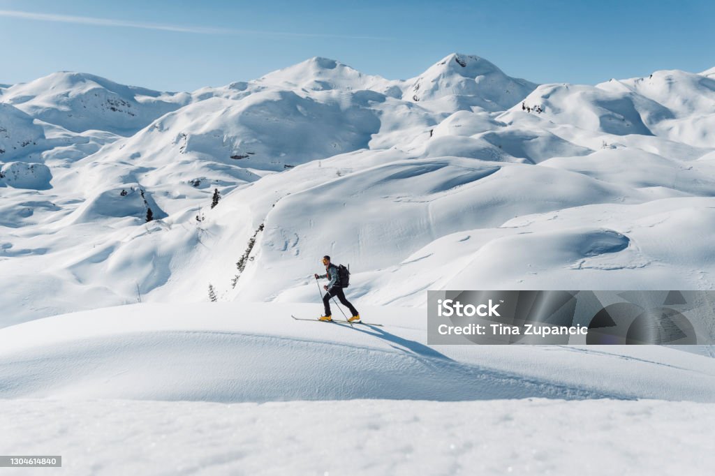 In the best company Back country skier, Caucasian. Perfect day in the mountains. Tranquil scene, copy space. He is looking around and admiring the beautiful mountains covered with snow and lit with sun. Above the tree line, glacier scene. Snow Stock Photo