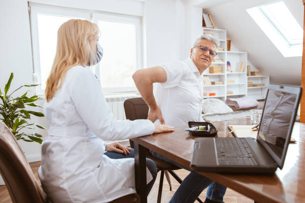Patient complains to the doctor of kidney pain Middle-aged man being examined by a female doctor in a doctor's office. Patient complains to the doctor of kidney pain. nephropathy photos stock pictures, royalty-free photos & images