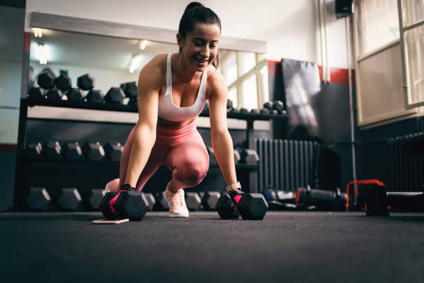 istock Young fit woman exercising in gym using dumbbells 1304619050