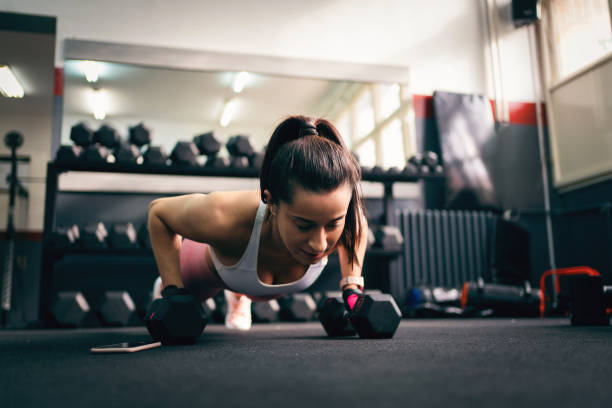 istock Young fit woman doing pushups on dumbbells in gym 1304619054