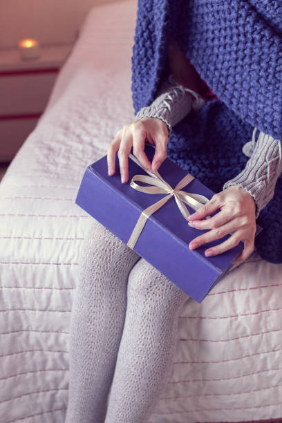 istock girl opens a gift while sitting on the bed 1304623599