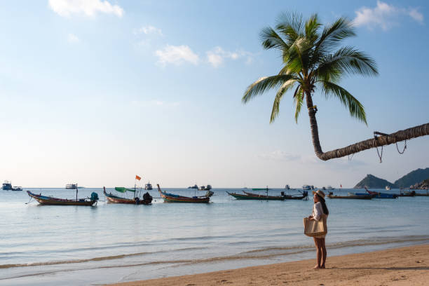 istock a woman with hat and bag strolling on the beach 1304635301