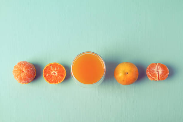 Fresh tangerine orange fruit and juice in glass on vintage color background