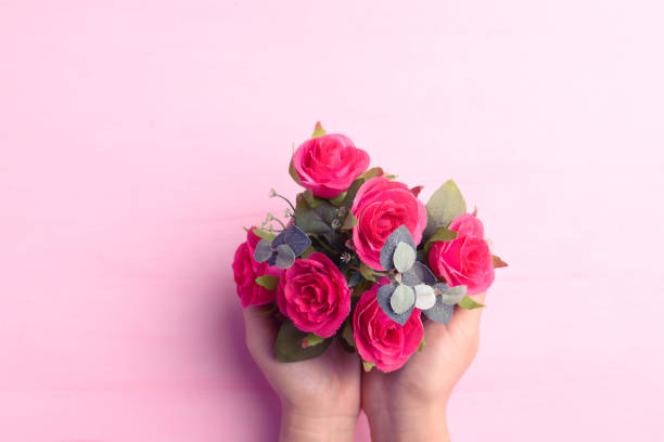 istock Hand holding red rose flower bouquet on pink background 1304635593
