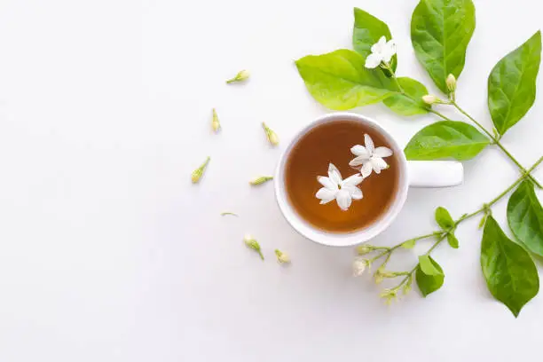 Photo of Jasmine tea with flowers jasmine in white cup on white wooden.