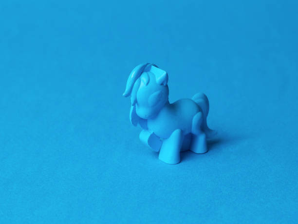 A blue pony toy on a blue background. Monochrome image of a fashionable toy.