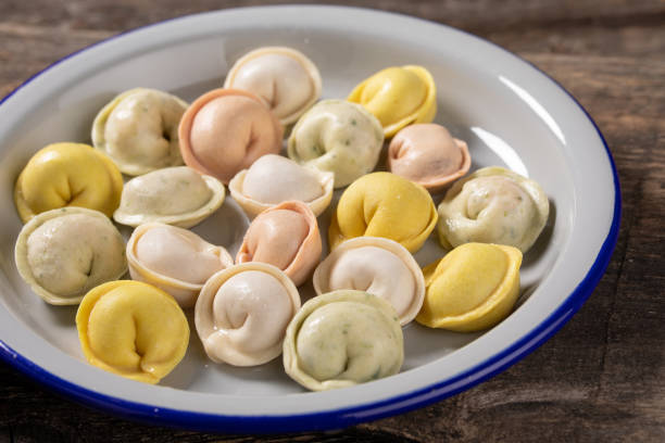 istock Traditional Russian dumplings made from multi-colored dough. Dumplings on a wooden board in an enamel plate. Cooking concept. 1304641226
