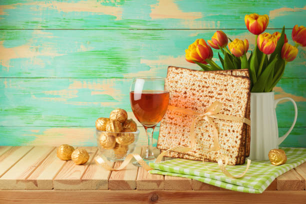 jüdische feiertag pessach-feier mit matzah, weinglas und tulpenblumen auf holztisch - passover seder seder plate table stock-fotos und bilder