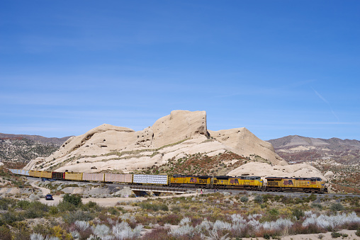 Cajon Pass, CA, USA - February 28, 2021: image a Union Pacific Railroad train traveling through the Mojave Desert shown against Mormon Rocks.. Union Pacific is the second largest railroad in the United States.