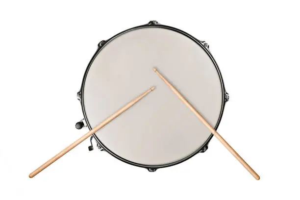 Photo of top view of a snaredrum and two drumsticks on white background