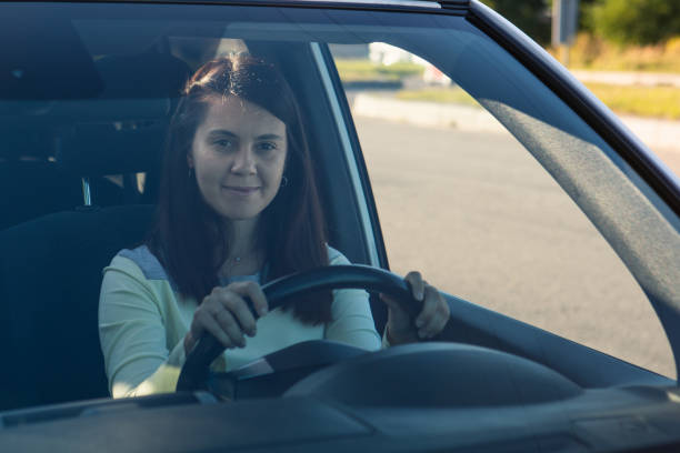 istock young pretty smiling woman driving car 1304659546