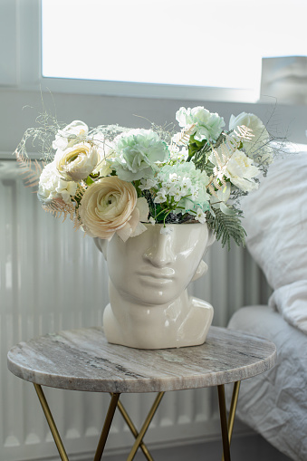 Flower composition in modern vase in home interior. Stylish trendy decoration