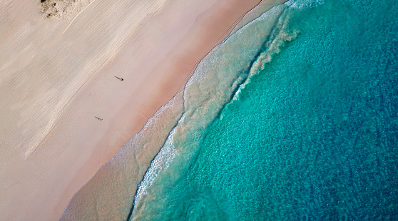 Directly above shot of couple relaxing on roof of campervan while enjoying at beach during summer vacation