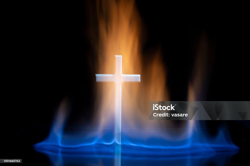 Cross or crucifix surrounded by burning fire flames. Cross or crucifix surrounded by burning fire flames. Religious theme. Pentecost - Religious Celebration Stock Photo