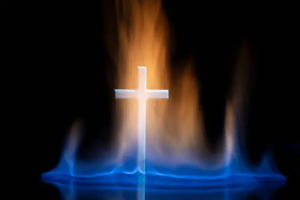 Cross or crucifix surrounded by burning fire flames. Religious theme.