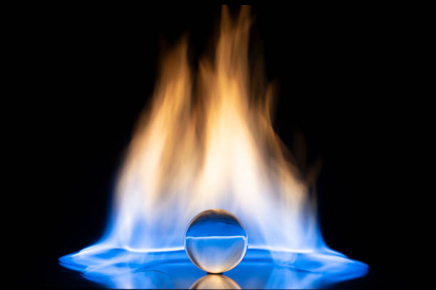 Glass ball with fire flames on black background. Copy space.