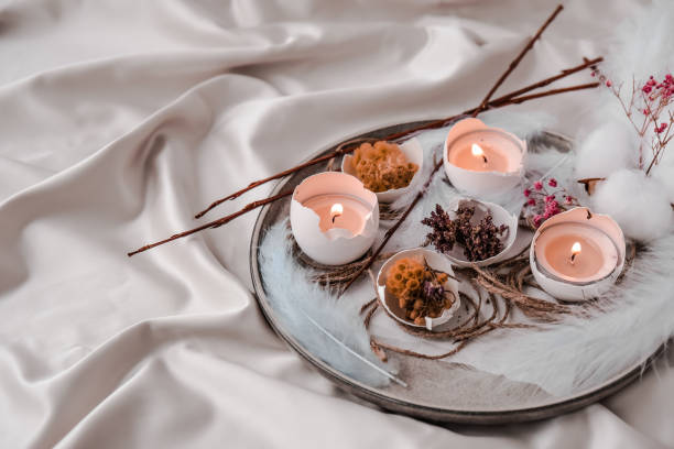 istock Trendy Easter decorations. Cracked organic eggs with dry grass flowers on plate. Candle light in White shell of the eggs. Bird feather. Copy space. Greeting easter card. Pastel colors 1304662555
