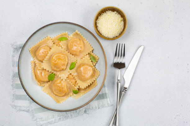 istock Italian dinner: tortelli stuffed with pumpkin and parmesan cheese, decorated with basil liaves. White background. Copy space. 1304664786