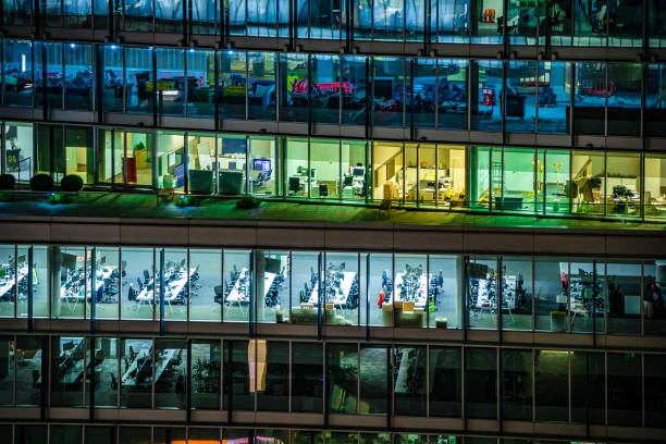 Close up of illuminated modern office building during night hours in London City, UK - creative stock photo Close up of highly detailed and illuminated modern office building during night hours in London City, UK, photographed on Canon EOS R full frame system. office window night stock pictures, royalty-free photos & images