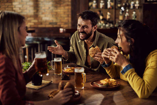 istock Cheerful friends talking while drinking beer and eating in a pub. 1304670679