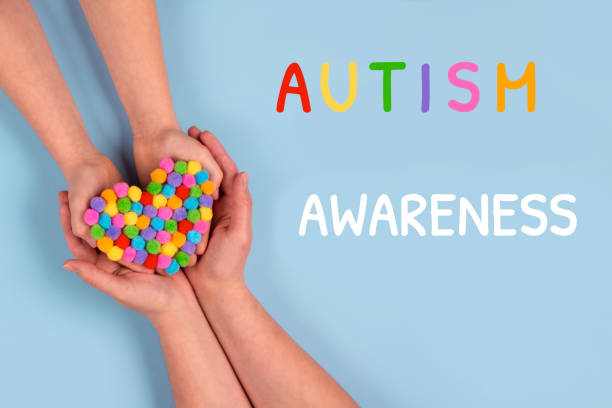 World Autism Awareness Day concept - autistic child's hands supported by mother holding multicolored heart on blue background. Autism spectrum disorder and child mental health concept, selective focus concepto del día mundial de concienciación sobre el autismo - manos de un niño autista apoyado por la madre que sostiene el corazón multicolor sobre el fondo azul. trastorno del espectro autista y concepto de salud mental infantil. enfoque selectivo