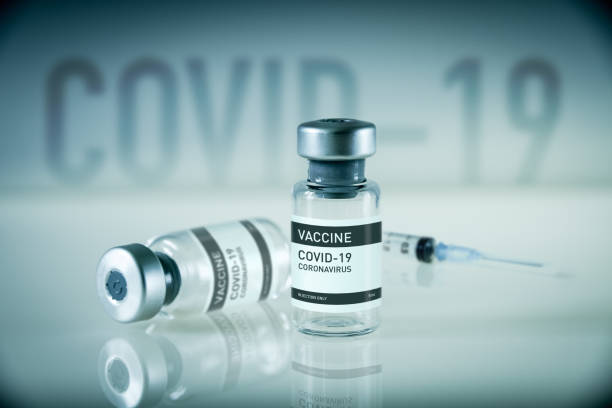 istock Covid-19 vaccine bottle and syringe on a blue background 1304672107