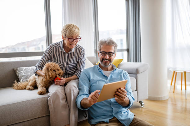 istock Lovely smiling mature couple having fun while using tablet at home 1304673097