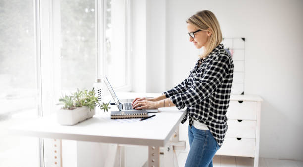istock Businesswoman working at ergonomic standing workstation. 1304673810