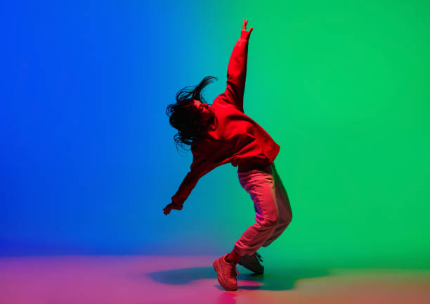 stylish sportive girl dancing hip-hop in stylish clothes on colorful background at dance hall in neon light. youth culture, movement, style and fashion, action. - dancing imagens e fotografias de stock