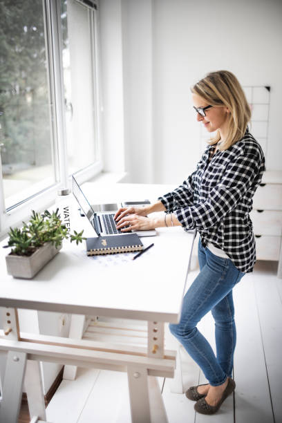 istock Businesswoman working at ergonomic standing workstation. 1304674498