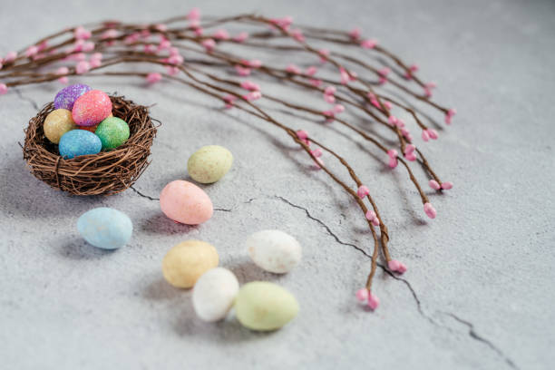 istock Colorful Easter eggs in bird's nest with decorative willow branches on gray cement background 1304675894