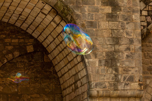 una bolla di sapone color arcobaleno vola sullo sfondo di un'antica parete in muratura. - leachate foto e immagini stock