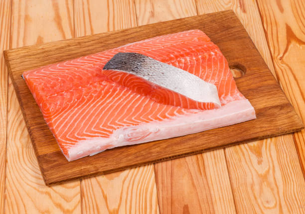 trozos de filete de salmón en la tabla de corte en la mesa rústica - vitamin d salmon fillet raw fotografías e imágenes de stock