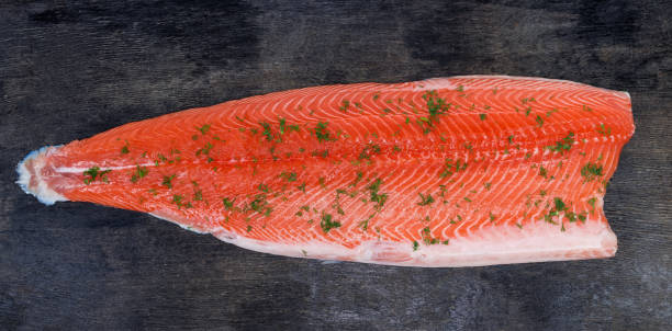 lachsfilet mit gehacktem dill auf dunkler oberfläche bestreut - vitamin d salmon fillet raw stock-fotos und bilder