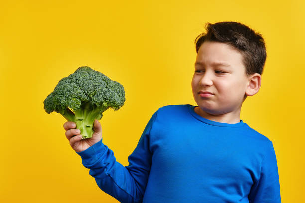 istock Child holding vegetable on yellow background 1304677364
