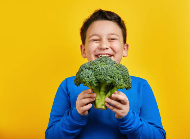 istock Child holding vegetable on yellow background 1304677389