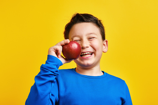 Child holding apple on yellow background